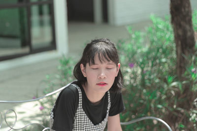 Young woman with eyes closed sitting in park