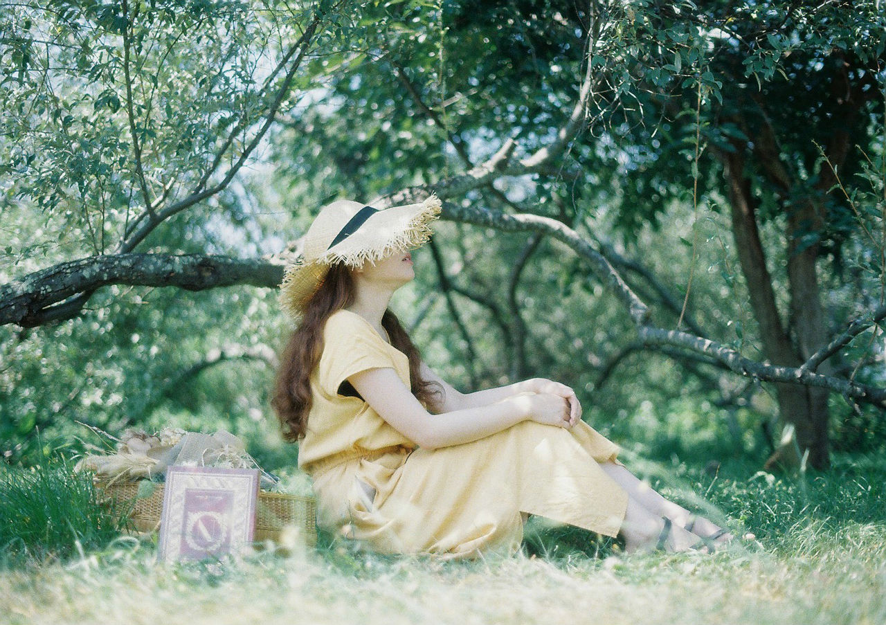SIDE VIEW OF A WOMAN SITTING ON PLANTS