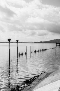 Wooden posts in sea against sky