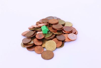 Close-up of coins with model home over white background