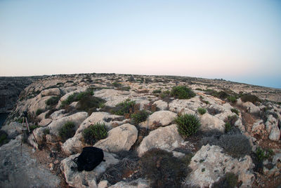 Scenic view of rocks against clear sky during sunset