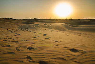 Scenic view of sand dunes against sky at sunset