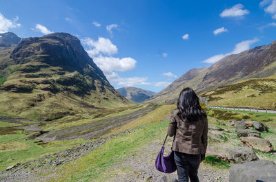 Rear view of woman walking on mountain against sky