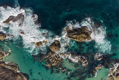 High angle view of waves splashing on rocks