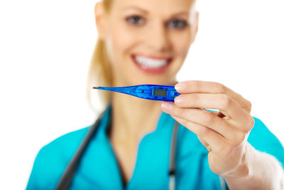 Close-up portrait of smiling nurse holding thermometer against white background