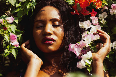 Content black woman smelling with flowers in park.