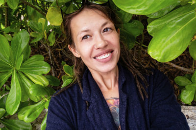 Funny smiling woman taking selfies among tropical leaves.