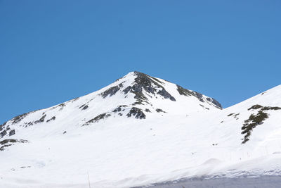 Snow covered mountain against clear blue sky