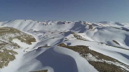 Scenic view of snow covered mountains against clear sky