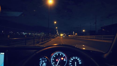 View of illuminated street seen through car windshield