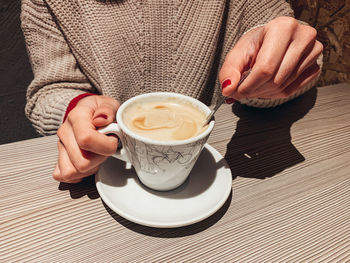 Midsection of woman holding coffee cup on table