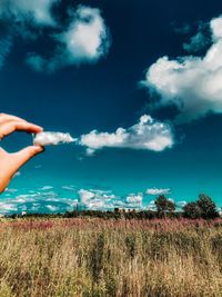 Person hand on field against sky