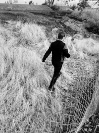 Rear view of man walking on field