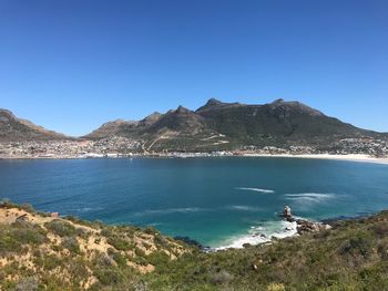 Scenic view of sea and mountains against clear blue sky