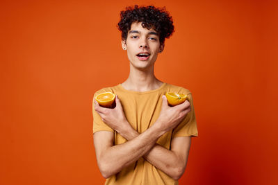 Portrait of smiling young man against orange background