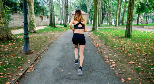 Rear view of woman running on footpath in park