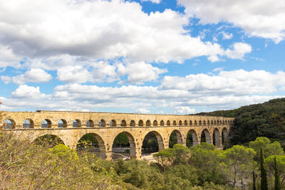 Arch bridge against cloudy sky