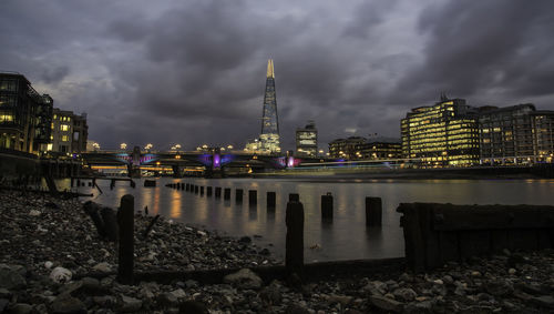 The shard skyscraper in illuminated city by thames river at dusk