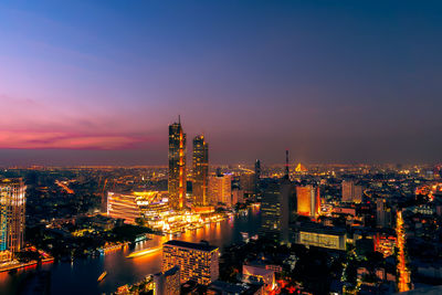 High angle view of illuminated buildings and cruise ship on large lake against sky at night