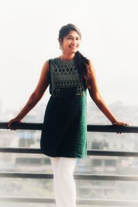 Portrait of smiling woman standing against railing