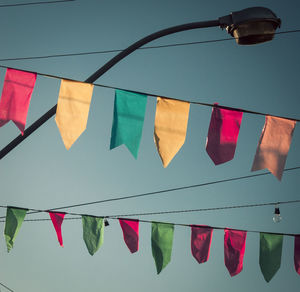 Low angle view of flags hanging against blue sky