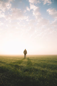 Man walking on field against sky during sunset