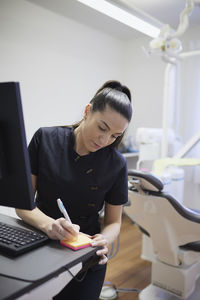 Female dentist writing in office