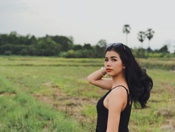 Portrait of beautiful young woman standing on field