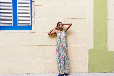 Full length of woman standing against wall