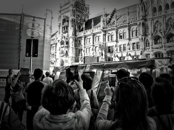 Rear view of people walking on sidewalk in city