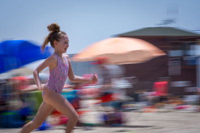 Side view of girl running at beach during summer