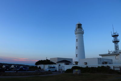 Lighthouse by buildings against blue sky