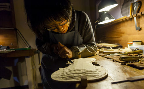 Female craftsman violin maker working on a new violin in the workshop