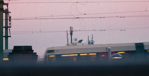 Electricity pylon by building in city against clear sky
