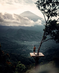 Man sitting on mountain against sky