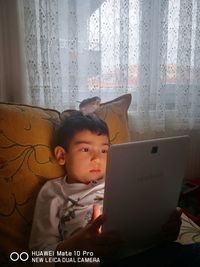 Boy looking at camera while sitting in laptop