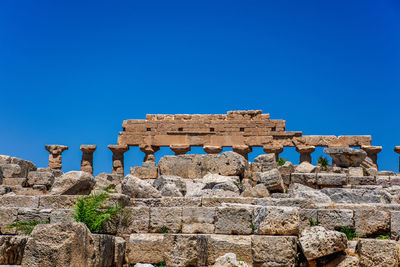 Low angle view of old ruins against clear blue sky