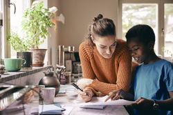 Mother assisting son while doing homework at home