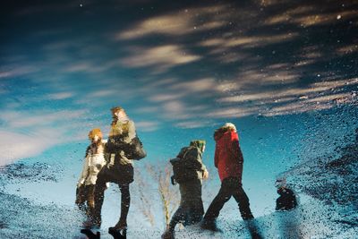 People on wet land against sky