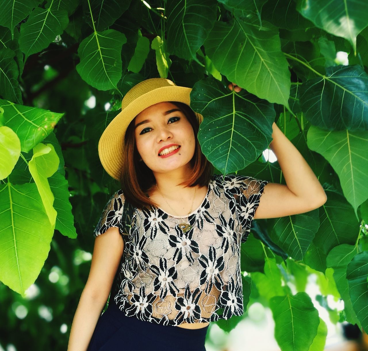 front view, one person, portrait, looking at camera, real people, leaf, leisure activity, young adult, standing, plant part, lifestyles, women, casual clothing, young women, beauty, plant, green color, waist up, beautiful woman, hair, hairstyle, outdoors, leaves