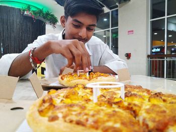 Close-up of man eating pizza at restaurant