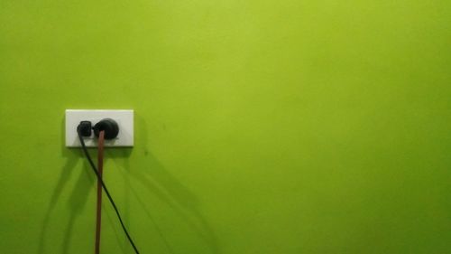 Low angle view of electric lamp against green wall