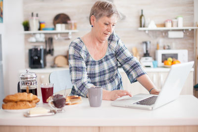 Senior woman using laptop on table at home