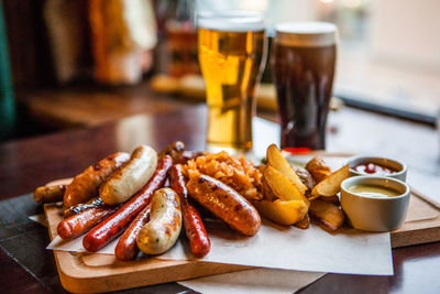 Close-up of sausages and french fries served with beers on table