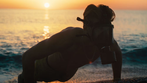 Man run at sunrise on the beach with gas mask