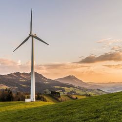 Windmills on field against sky during sunset