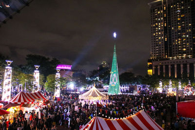 Crowd on illuminated city against sky at night