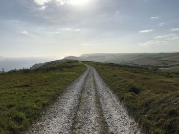 Road leading towards landscape against sky