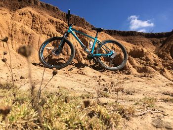 Bicycle parked on field against sky