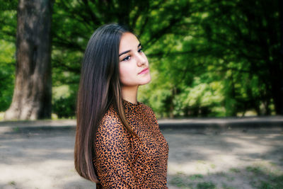 Young woman standing against trees